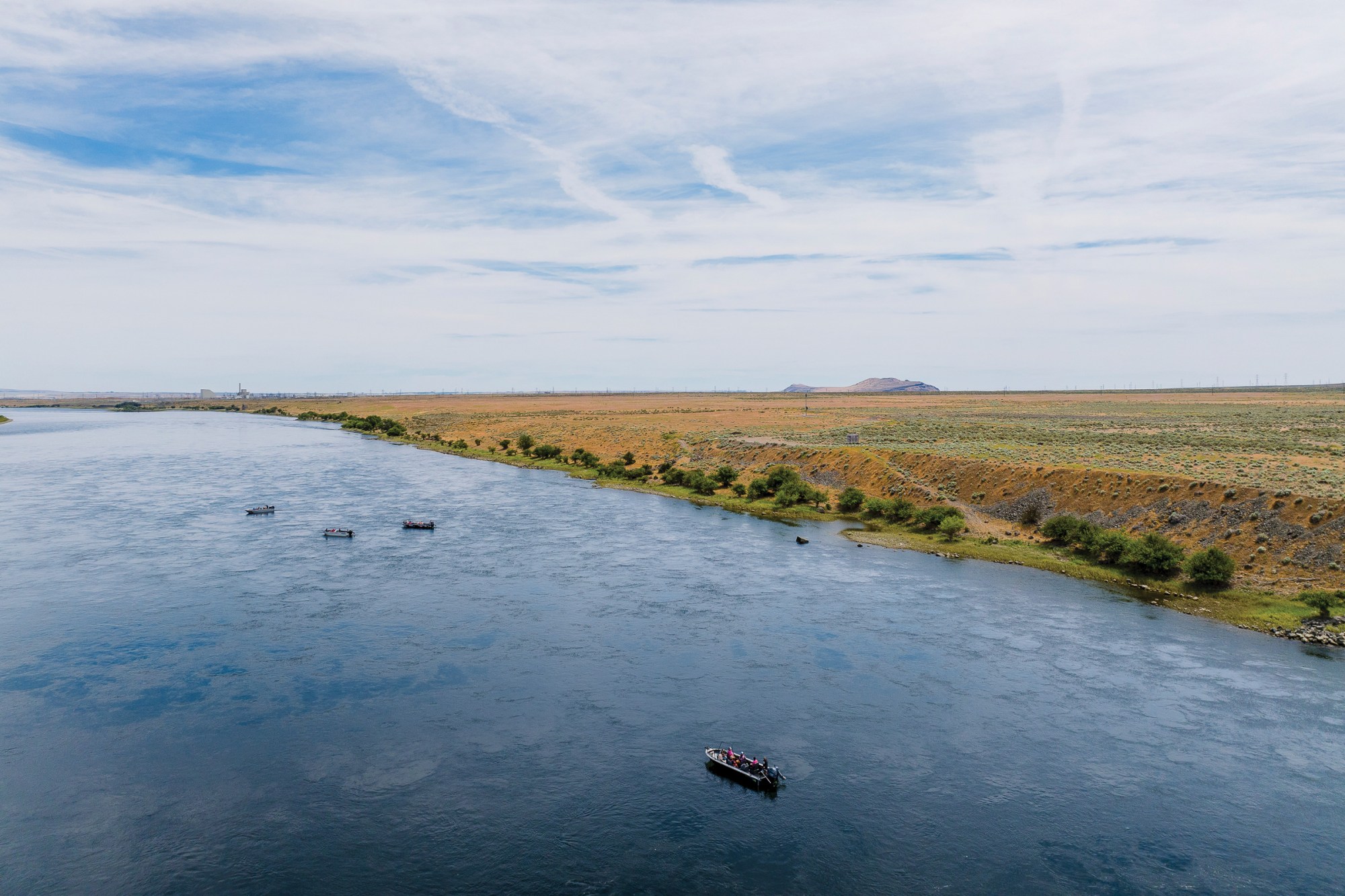Boats carry Hanford Journey attendees down the Columbia River in Washington toward Hanford reactors, one that’s cocooned and another that’s decommissioned but still standing.