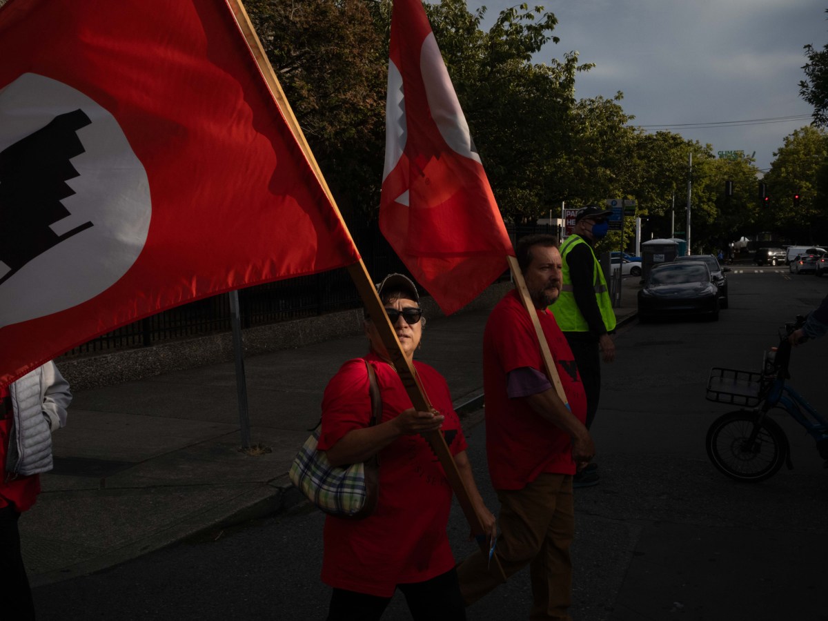 Two labor advocates wave United Farm Workers flags at the rally in Seattle on August 31.