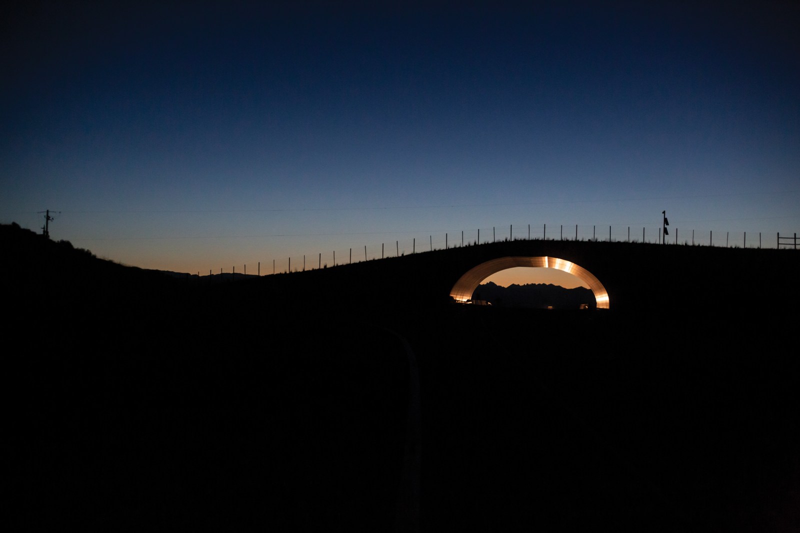 The Trappers Point overpass, illuminated by early-morning vehicle traffic, was built in 2012 to help reduce wildlife-vehicle collisions along important mule deer and pronghorn migration routes west of Pinedale, Wyoming.