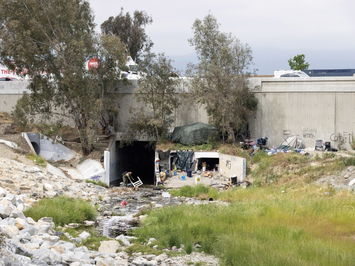 An unhoused community lives along a flood-control channel that runs under Interstate 10 in Ontario, California.